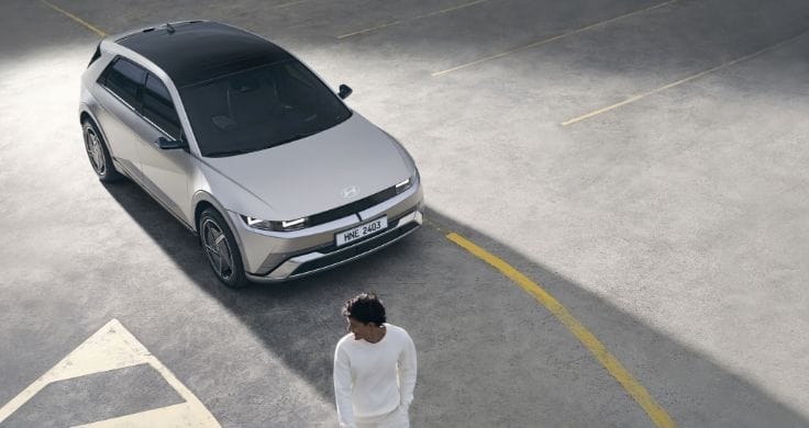 An IONIQ 5 is parked next to a man.